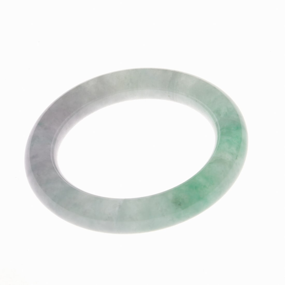 Jade Bangle: Jade Bangle China, 20th century. Green jade with attractive, dark and white cloud-like inclusions. Weight: 96 g. Diameter: 8.4 cm, inner diameter: 5.9 cm. Natural cracking / cracks.