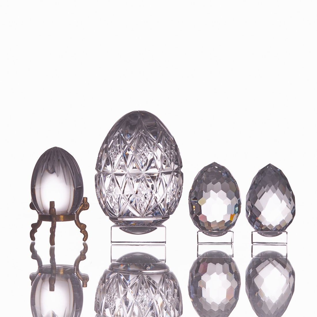 2 Baccarat egg and 2 eggs. Baccarat, Nancy late 20th century and others.: 2 Baccarat egg and 2 eggs Baccarat, Nancy late 20th century and others. 1 egg: colorless glass, faceted at the top. Etched stamp: BACCARAT FRANCE. H. 6 cm. Brass stand: total height: 8.5 cm -- 2 eggs: