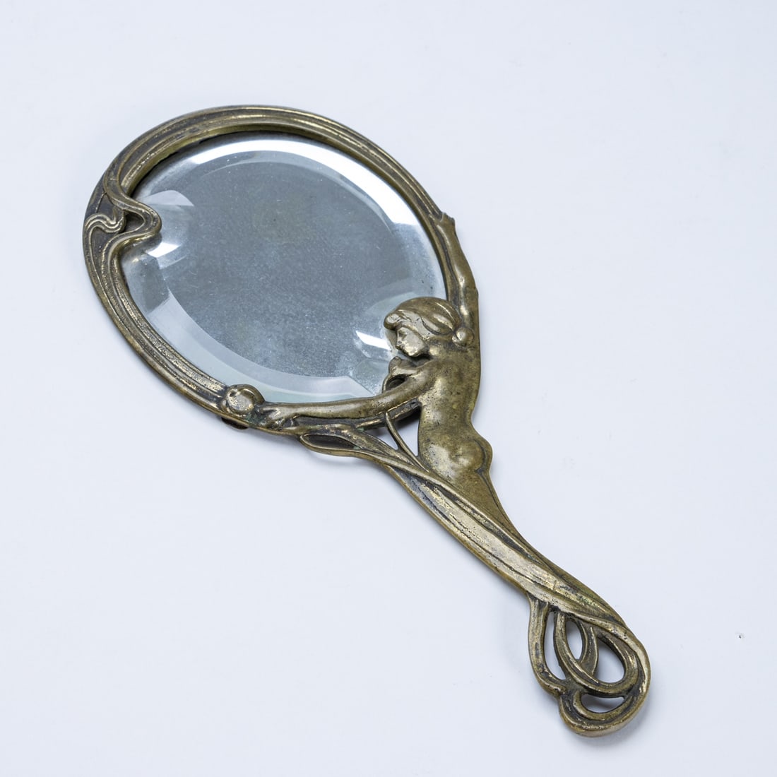 Art Nouveau hand mirror: Art Nouveau hand mirror Probably German, circa 1900. Brass, 25cm x 10.5cm. Beautiful filigree hand mirror with a female figure holding the ground mirror. The motif has been frequently copied and is