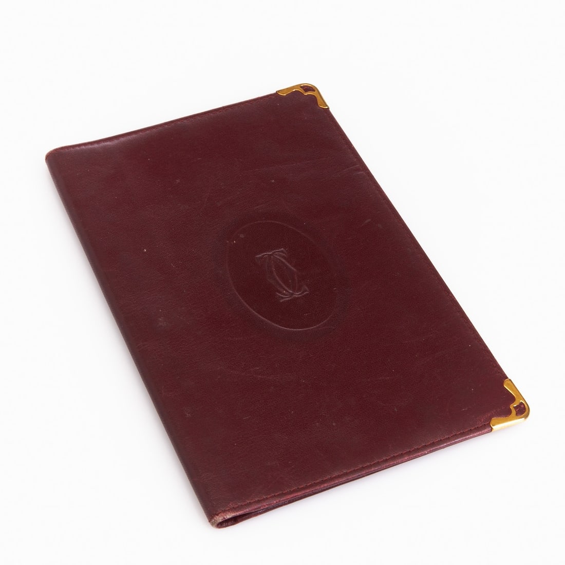 Cartier - Elegant document or ID case: Cartier - Elegant document or ID case "Les Must de Cartier", 1980s/90s, Paris. Bordeaux-colored leather with gold-colored corner fittings and blind-embossed Cartier monogram. Interior with