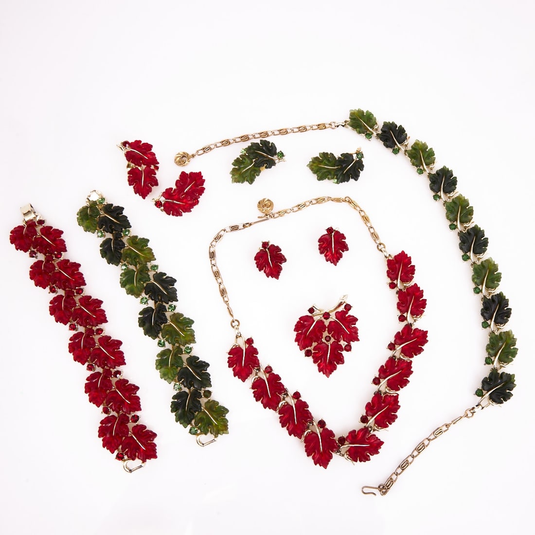 LISNER - Two Vintage Parures in Green/Red with Foliage Motif (8 pieces): LISNER - Two Vintage Parures in Green/Red with Foliage Motif (8 pieces) 2 necklaces, 2 bracelets, 1 brooch and 3 pairs of clip-on earrings. Lisner, New York, USA. Circa 1960-1990. Metal, white gold-co