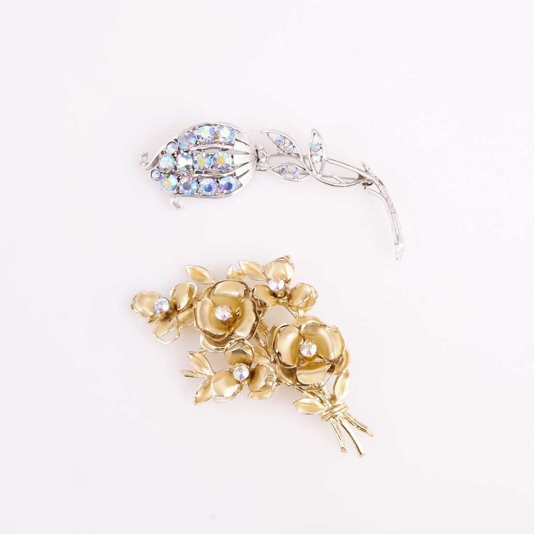 CORO - Two vintage brooches with Aurora Borealis colored rhinestones: CORO - Two vintage brooches with Aurora Borealis colored rhinestones Coro Jewelry, Cohn & Rosenberger, New York, USA. Circa 1940 - 1950s. Metal, silver- / gold-colored; Aurora Borealis colored rhi