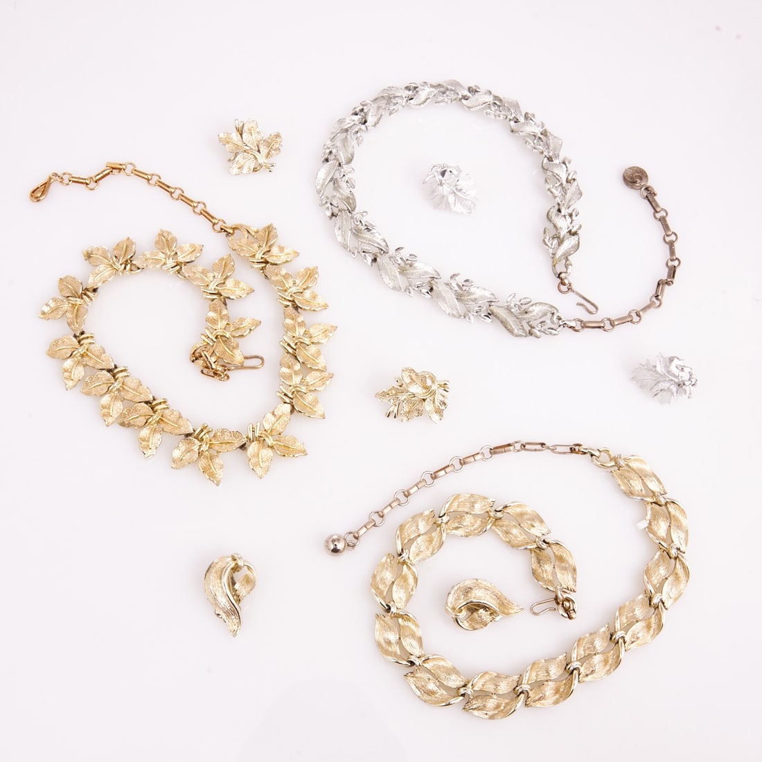 LISNER - Three Vintage Parures with Leaf / Feather Motifs (6 pieces): LISNER - Three Vintage Parures with Leaf / Feather Motifs (6 pieces) 3 necklaces and 3 pairs of ear clips. Lisner, New York, circa 1950. Metal, gold- / silver-colored; total weight: 209 g. Dimensions: