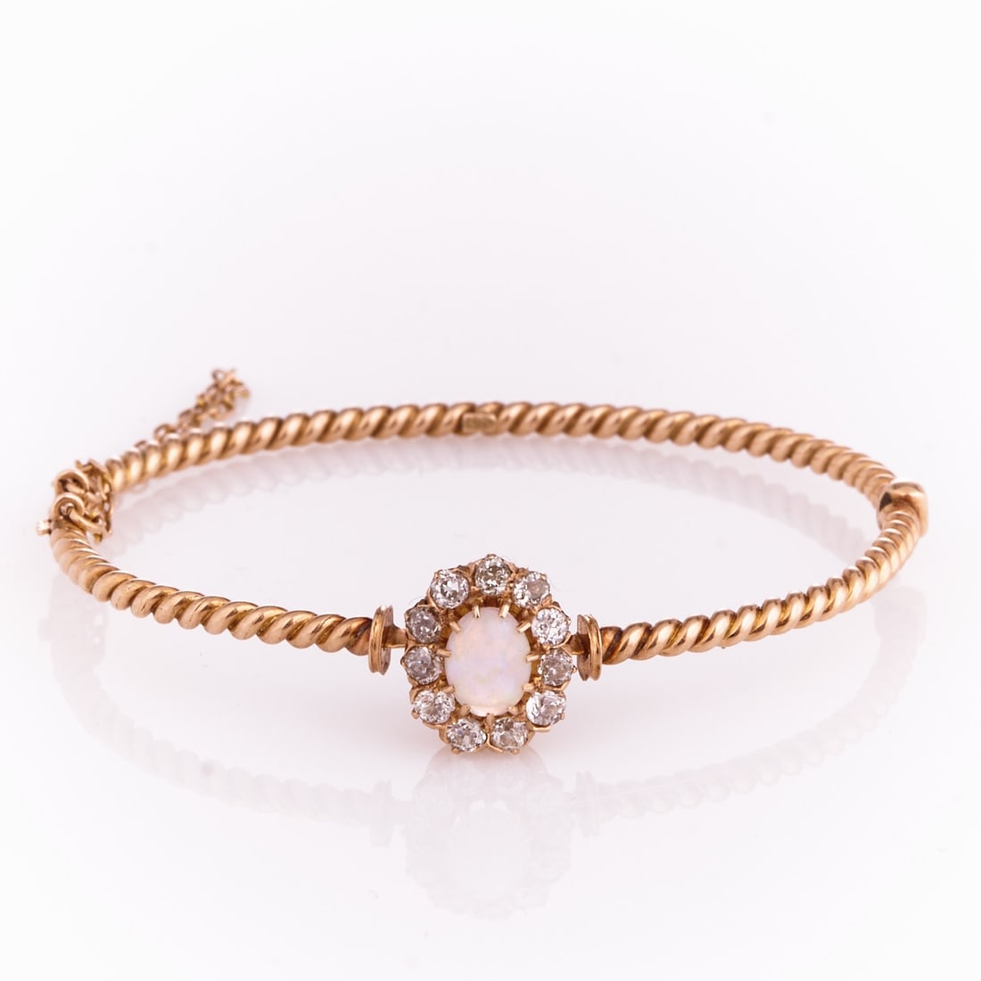 Antique bangle with opal and diamonds entoured: Antique bangle with opal and diamonds entoured Probably Berlin, around 1900. 585/- rose gold, stamped. Weight: 10.1 g. 1 cabochon-cut opal (0.7 x 0.5 cm). 11 old-cut diamonds totalling approx. 0.5 ct.