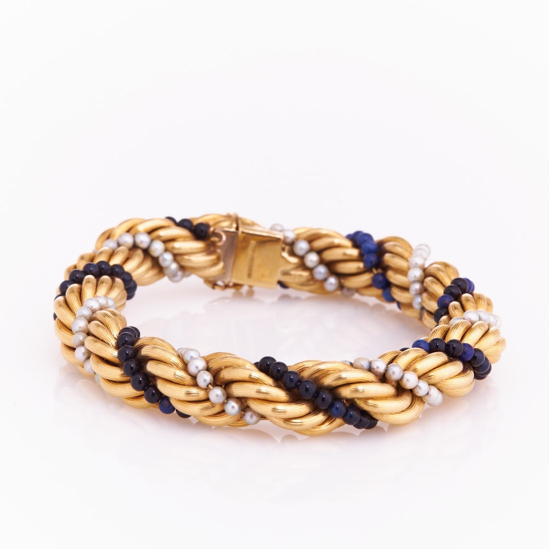 Cord bracelet with lapis lazuli and pearls: Cord bracelet with lapis lazuli and pearls Mid-Century. 750/- yellow gold, stamped. Weight: 57 g. Various lapis lazuli beads. Various pearls. Length 21.5 cm. Width 1.2 cm. Box clasp with safety eight.