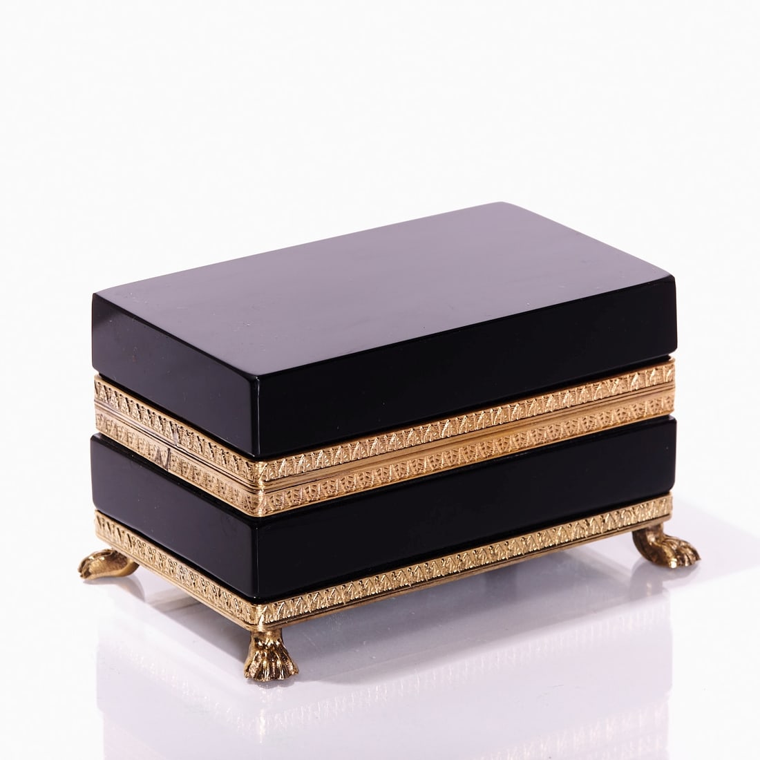 Rectangular lidded box on mounting with lion's feet - Art D?©co. France, circa 1935-1940.: Rectangular lidded box on mounting with lion's feet - Art Déco France, circa 1935-1940. Thick-walled, black glass, cut and polished. Gilded brass mounting with hinge. Relief mounting with acant