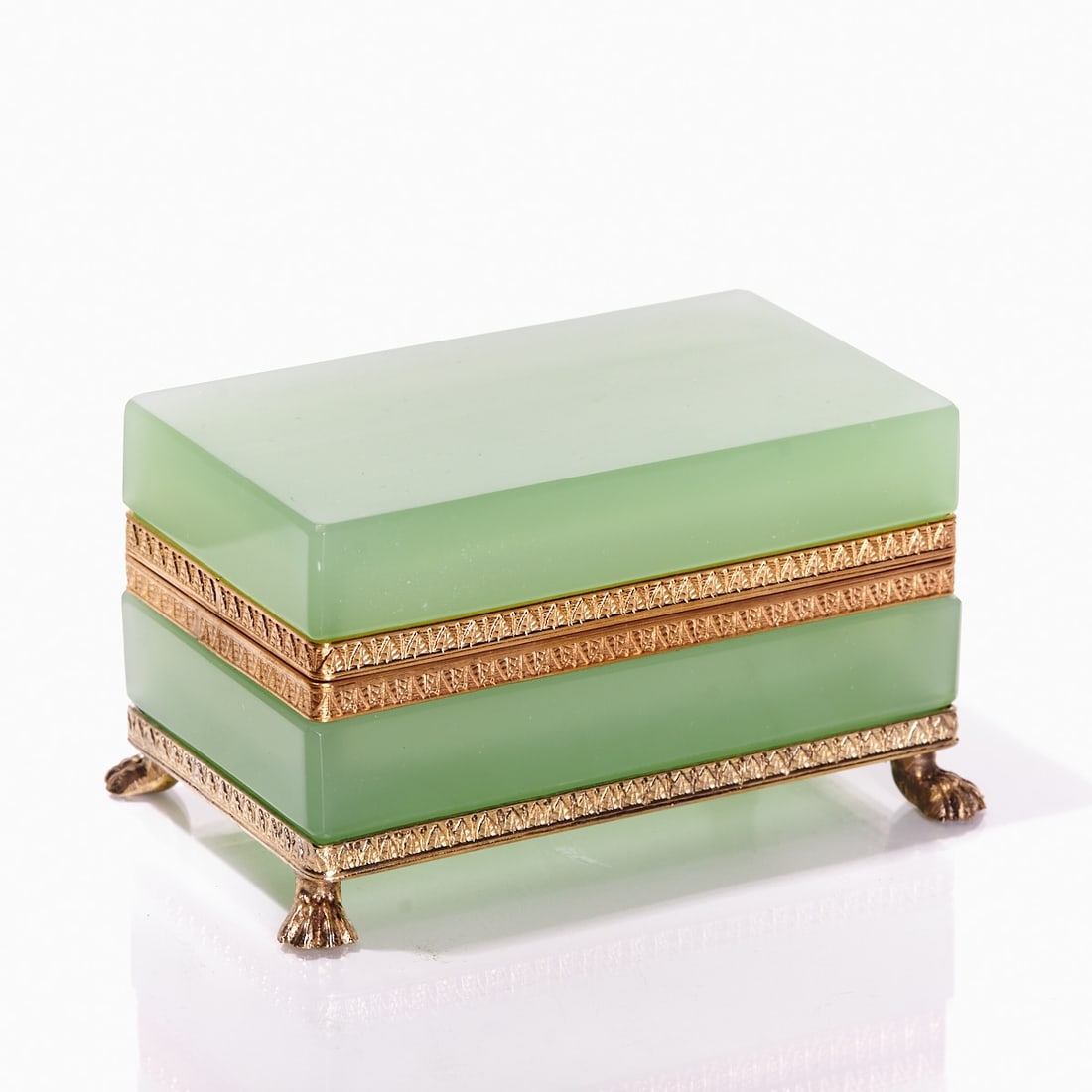 Rectangular lidded box on mounting with lion's feet - Art Deco. France, circa 1935-1940.: Rectangular lidded box on mounting with lion's feet - Art Deco France, circa 1935-1940. Thick-walled, green opal glass, slightly translucent, cut and polished. Gilded brass mounting with hinge. Emboss