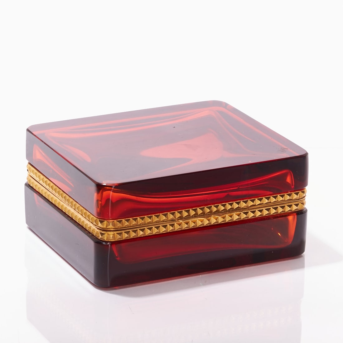 Rectangular covered box - Art Deco. France, circa 1935-1940.: Rectangular covered box - Art Deco France, circa 1935-1940. Thick-walled, amber-colored glass, cut and polished. Gilded brass mounting with hinge and pyramid relief. H. 5.8 cm, 11 x 12.5 cm.
