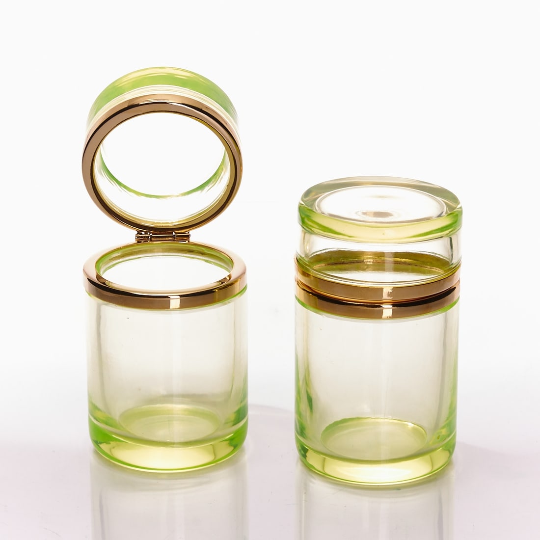 Pair of round, tall covered boxes - Art D?©co. France, circa 1935-1940.: Pair of round, tall covered boxes - Art Déco France, circa 1935-1940. Uranium glass: Thick-walled, green glass (apple green), cut and polished. Gilded brass mounting with hinge. H. 10.5 cm, D. 
