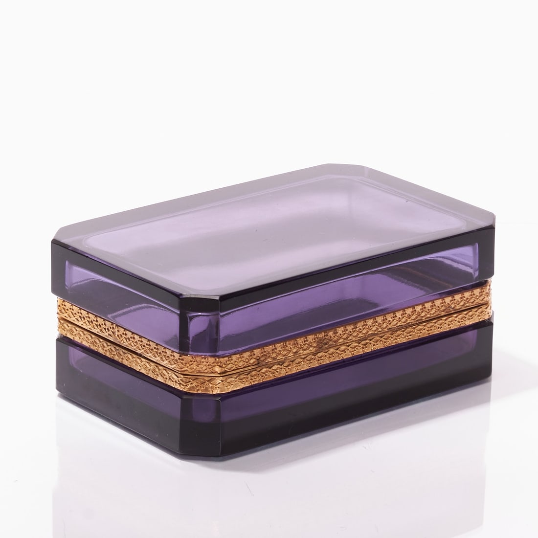 Octagonal lidded box - Art Deco. France, circa 1935-1940.: Octagonal lidded box - Art Deco France, circa 1935-1940. Thick-walled, purple glass, ground and polished. Edges ground. Gilt, decorated brass mounting with hinge. H. 5.5 cm, 8.5 x 13.5 cm. - Condition