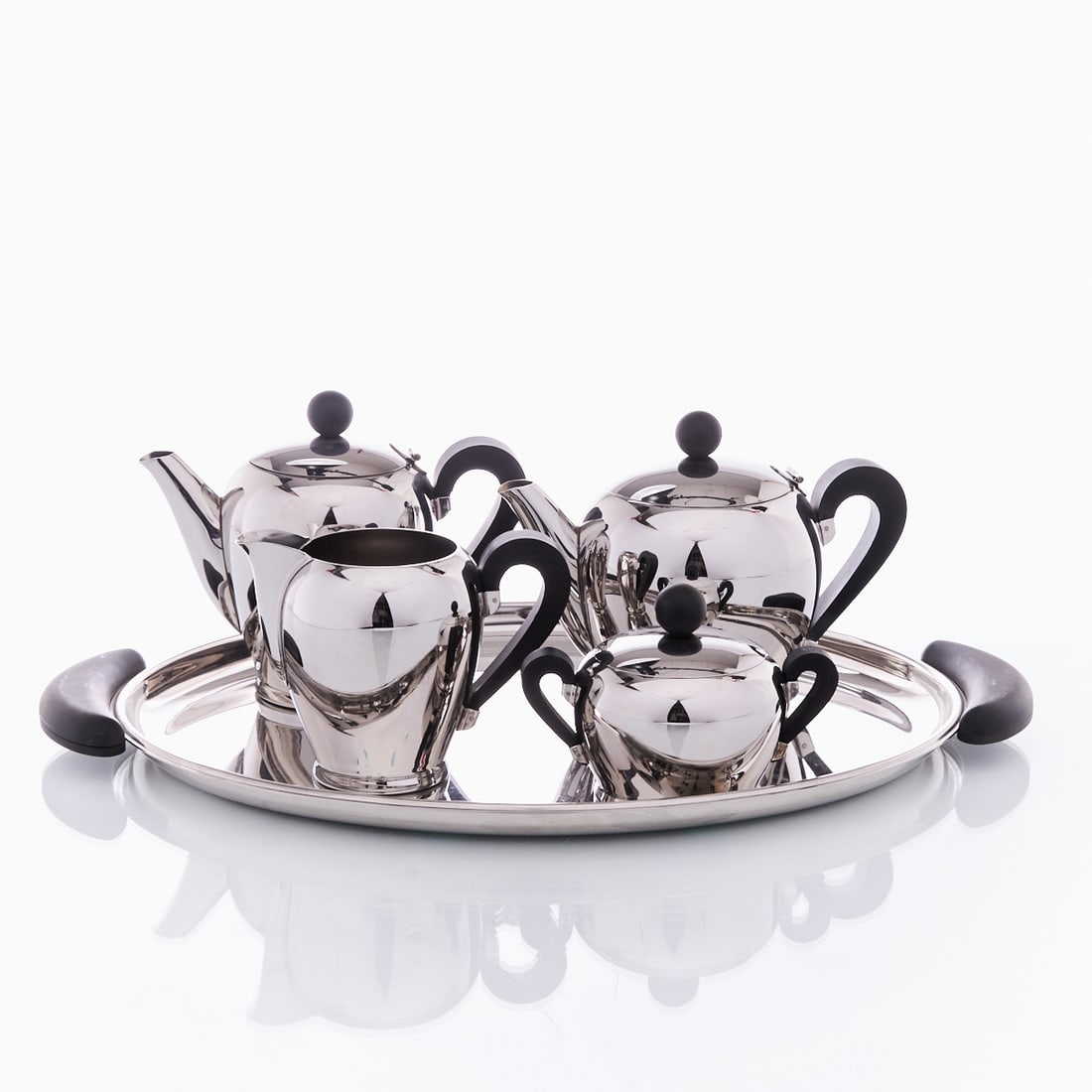 Alessi 'Bomb?©' Coffee and Tea Set: Alessi "Bombé" Coffee and Tea Set Italy, designed by Carlo Alessi, 1945. 18/10 stainless steel, highly polished. Bakelite. Dimensions: Tray 50 x 33.5 cm, Teapot H. approx. 16 cm. Mult