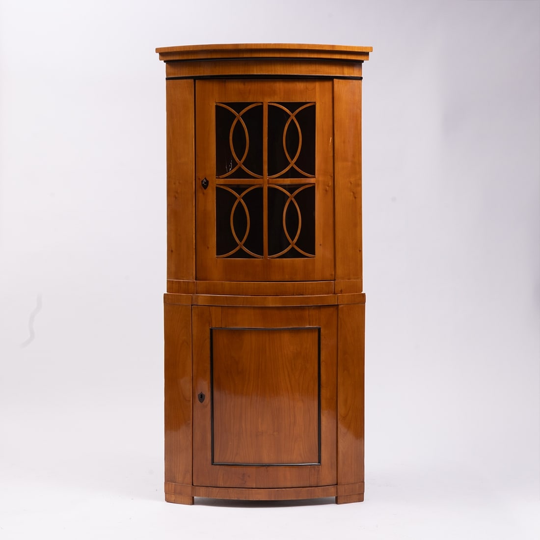 Biedermeier Corner Cabinet: Biedermeier corner cabinet Germany, circa 1840. Cherry. 200 x 94 x 55 cm. Damaged. On block feet. Bombe body with two doors. Finished with a profiled cornice. Partially ebonized.