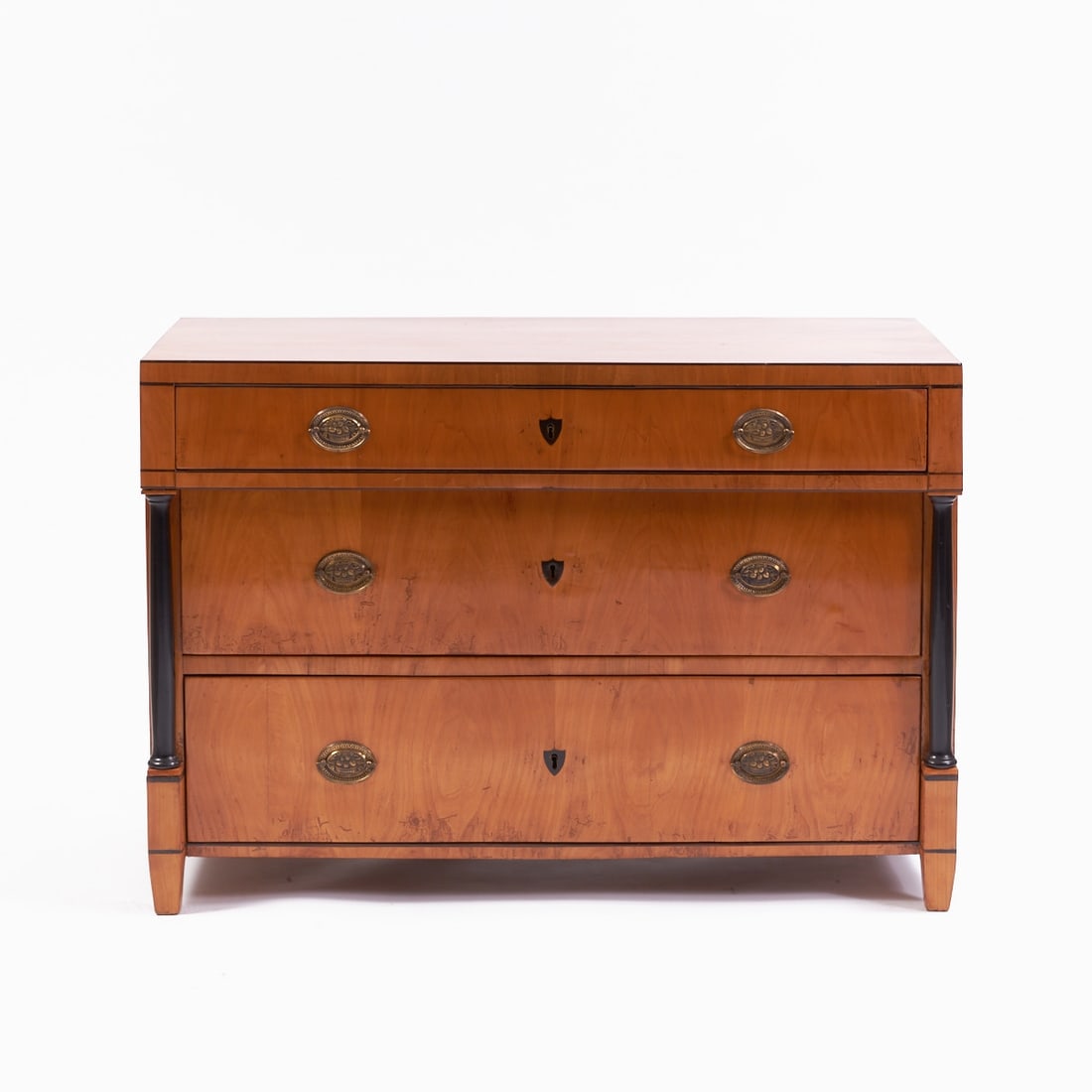 Biedermeier Commode: Biedermeier Commode Germany, circa 1820. Cherry. 80 x 116 x 57.5 cm. On four conical feet with a straight frame. Rectangular body with three drawers, flanked by ebonized columns. Finished with a