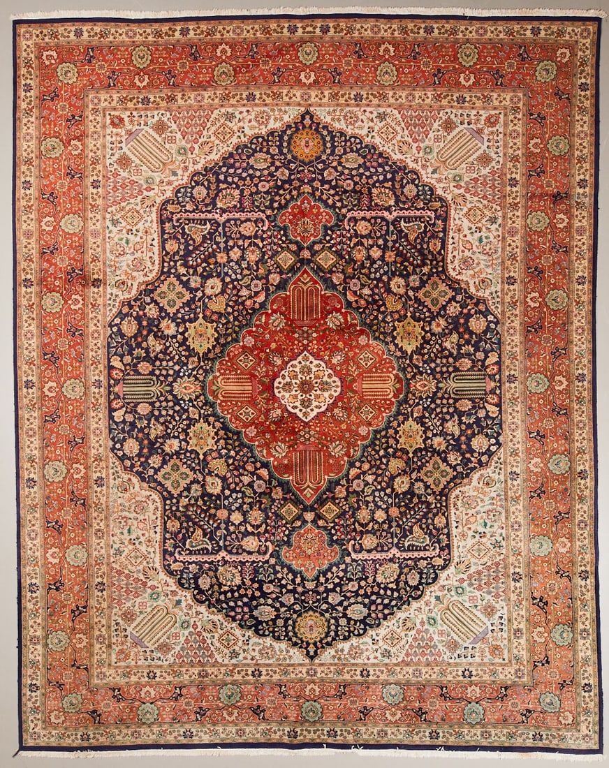 Tabriz: Tabriz rug Persia, 20th century. Wool on cotton, approx. 375 × 300 cm. Finely knotted rug with a dark blue central field and a large central medallion in coral red, cream, and blue. Rich, finely