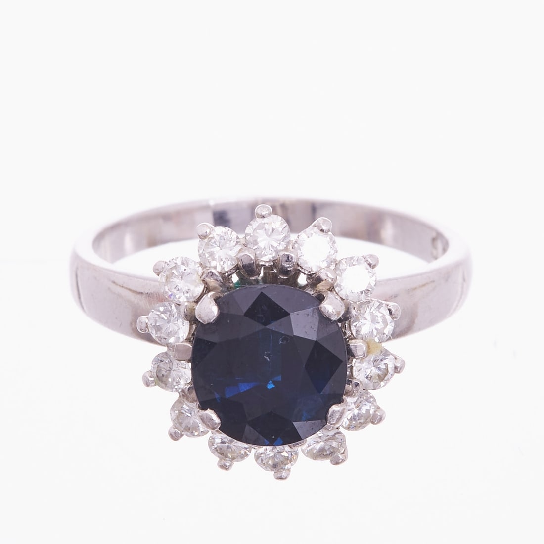 Classic Sapphire and Brilliant-Cut Diamond Ring: Classic sapphire and brilliant-cut diamond ring 585/- white gold, stamped. Total weight: 5.6 g. Centrally set sapphire of 6.56 ct in round cut, surrounded by 14 brilliant-cut diamonds totaling