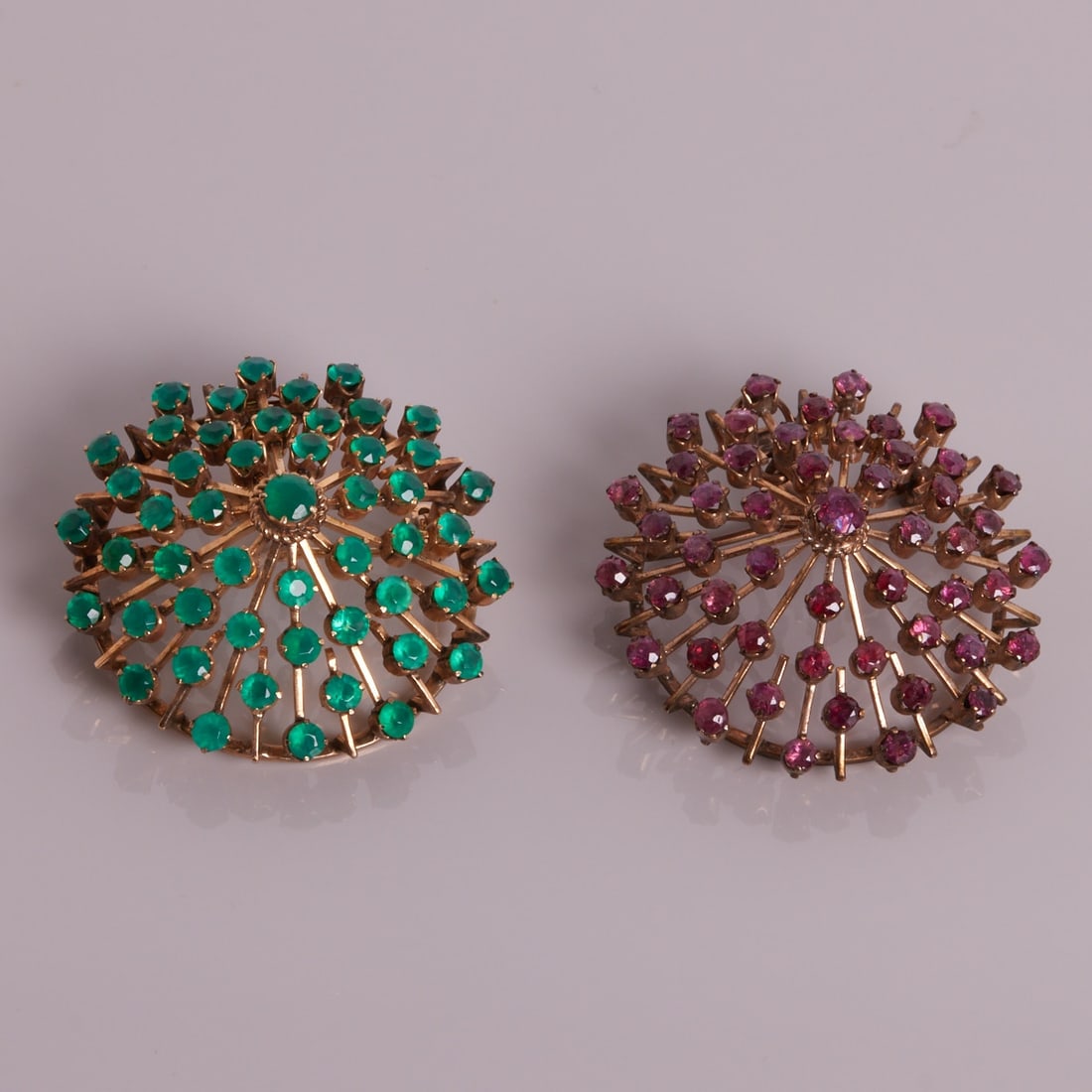 Pair of brooches/pendants with rubies and emeralds: Pair of brooches/pendants with rubies and emeralds Emerald brooch: 750/- yellow gold, hallmarked. Weight: 14.6 g. Hallmark: 18. Various round cut emeralds. Dimensions: 4.5 x 4 cm. Eyelet and pin with