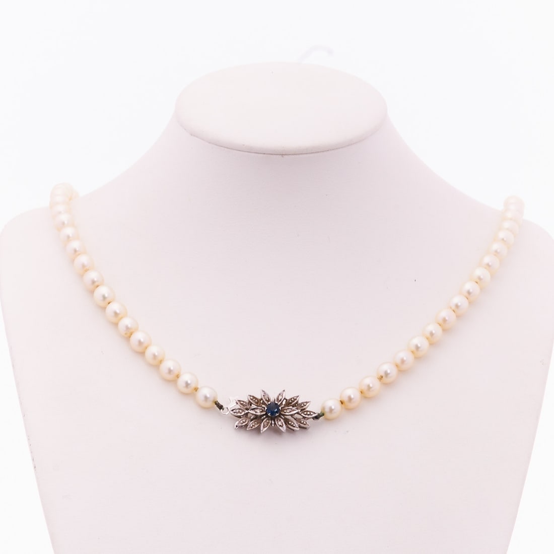 Pearl Necklace with Sapphire and Diamond Clasp: Pearl Necklace with Sapphire and Diamond Clasp 750/- white gold, stamped. Weight: 25.88 g. 1 sapphire in Swiss cut, approx. 0.15 ct. 6 small brilliant-cut diamonds. 64 cultured pearls, D. approx. 8.3
