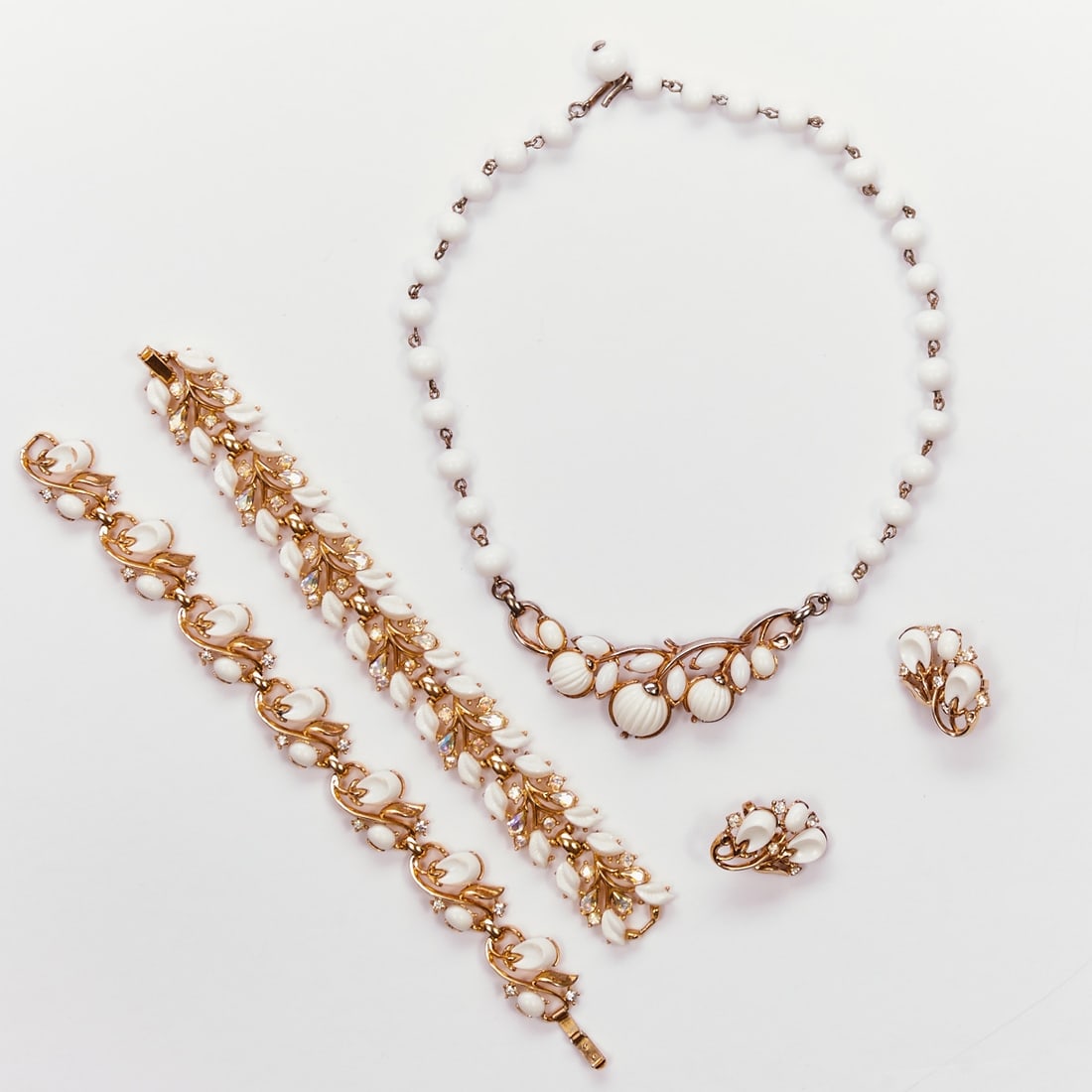 TRIFARI Alfred Philippe - Vintage ''Pebble Beach'' Jewelry Set (4 pieces): TRIFARI Alfred Philippe - Vintage ''Pebble Beach'' Jewelry Set (4 pieces) Necklace, 2 bracelets and 1 pair of ear clips. New York, 1956. Metal, gold-colored with rhinestones and white thermoset. Weigh
