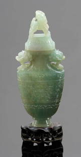 Jadeitobjekt als Vase China, um 1900. Jade auf ...: Jadeobjekt als Vase China, um 1900. Jadeit. Holzsockel. H. m. Sockel 20 cm. Deckelvase mit Wolkenbanddekor auf den Schauseiten. Seitliche Handhaben mit Ringen, Deckel mit Fo-Hund als oberer Abschluss.