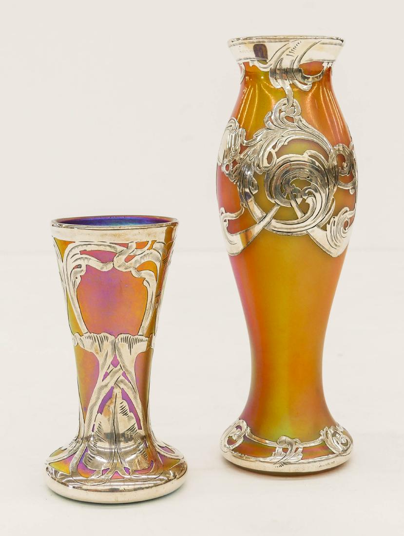 2pc Quezal & Loetz Silver Overlay Iridescent Glass: 2pc Quezal & Loetz Silver Overlay Iridescent Glass Cabinet Vases. Includes a taller loetz vase 7''x2.5'' and a smaller marked Quezal vase 4.25''x2''. Excellent condition. Art nouveau style.