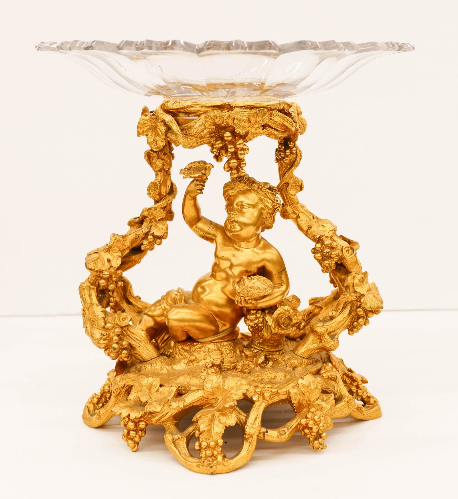 Antique French Dore Bronze Putto Centerpiece: Antique French Dore Bronze Putto Centerpiece 9.5''x9.5''. Impressive gitlt bronze putto with grape vine motif. Cut glass compote topper is as-is. It has a 2.5'' diameter opening at top. 19th century.