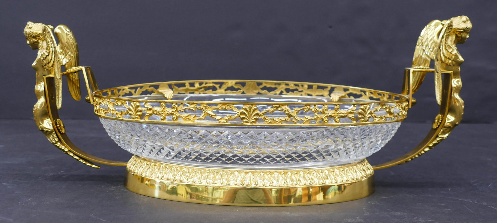 French Ormolu Mounted Cut Glass Centerpiece Bowl: French Ormolu Mounted Cut Glass Centerpiece Bowl 8''x20''. A fine diamond pattern heavy cut glass bowl with ormolu mounted handles of winged women. Unmarked. One handle sits slightly lower. Overall ex