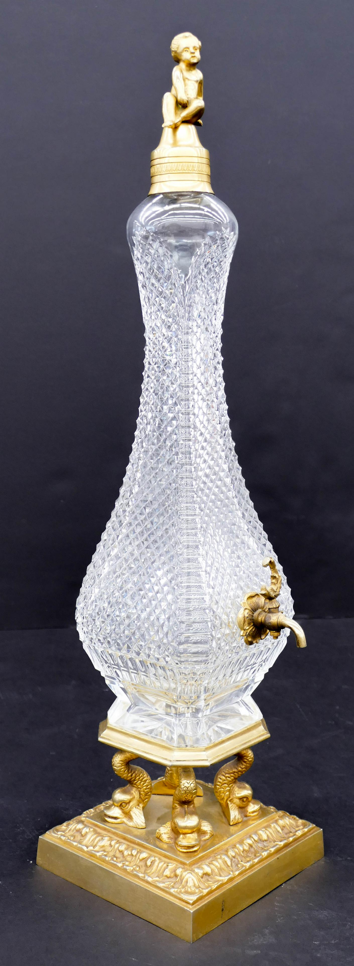 Italian Ormolu Mounted Cut Glass Wine Dispenser: Italian Ormolu Mounted Cut Glass Wine Dispenser 24''x6''. A heavy cut diamond pattern dispenser with figural putto finial and dolphin pedestal. Unmarked. Excellent condition. (H)