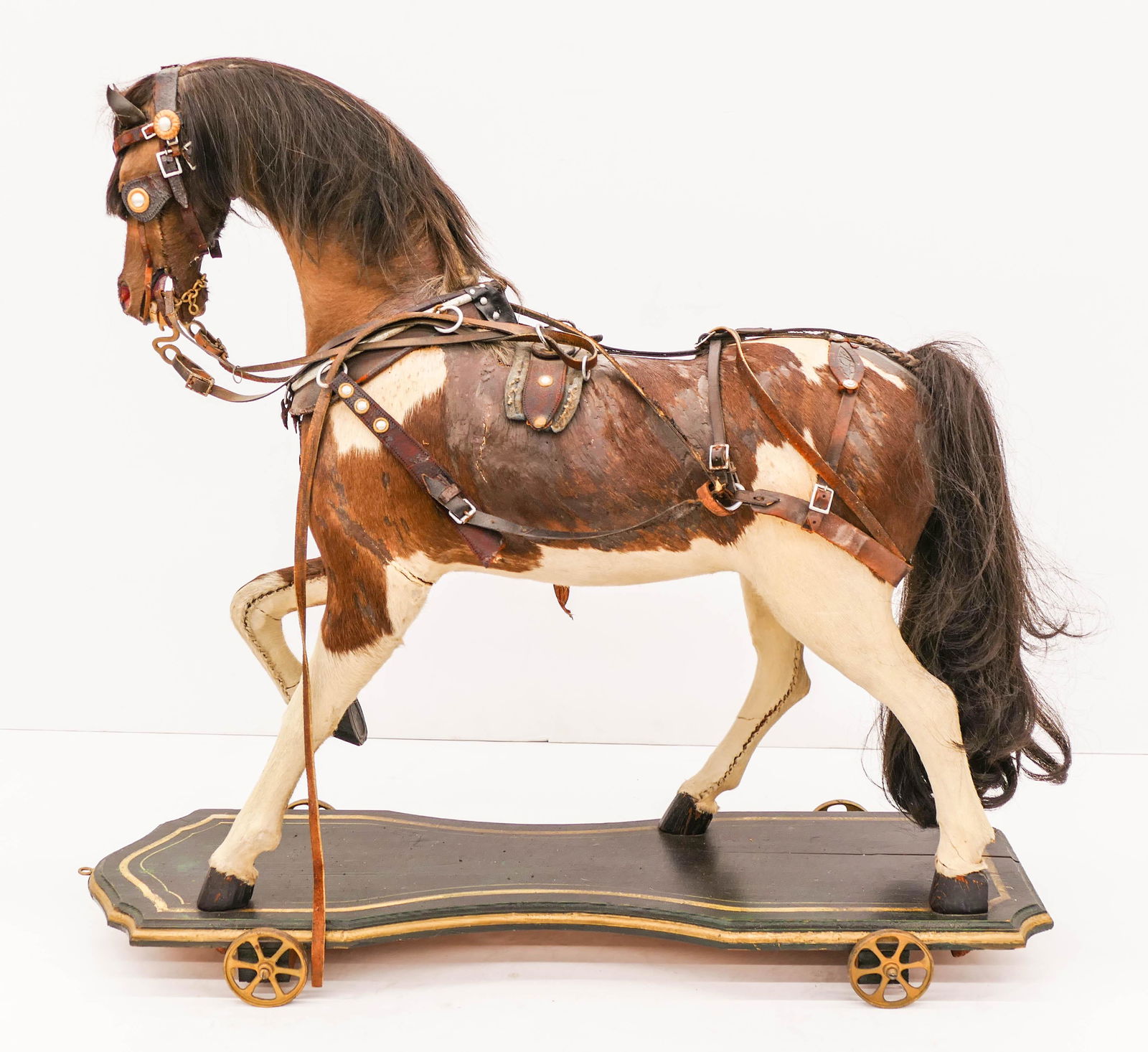 Antique Horse Model Ride On Pull Toy 30''x32''.: Antique Horse Model Ride On Pull Toy 30''x32''. Impressive horse hair over wood model with leather bridle and glass eyes. Painted wood folk art platform with steel wheels painted gold. Scattered wear