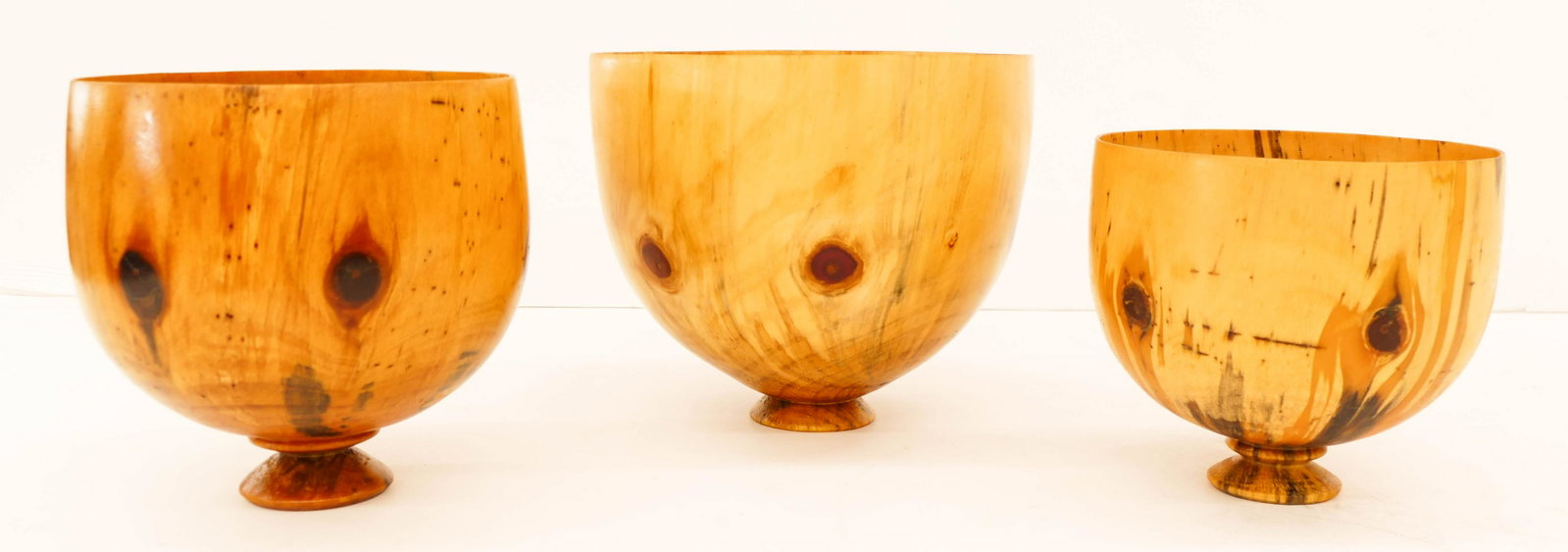 3pc Jonathan Somaoang Hawaiian Norfolk Pine Footed: 3pc Jonathan Somaoang Hawaiian Norfolk Pine Footed Bowls 7'' to 8.5'' Tall. A trio of hand turned wood vessels from Hawaii. Signed and inscribed on bottom. Excellent condition. Widths are 8'' to 10''.