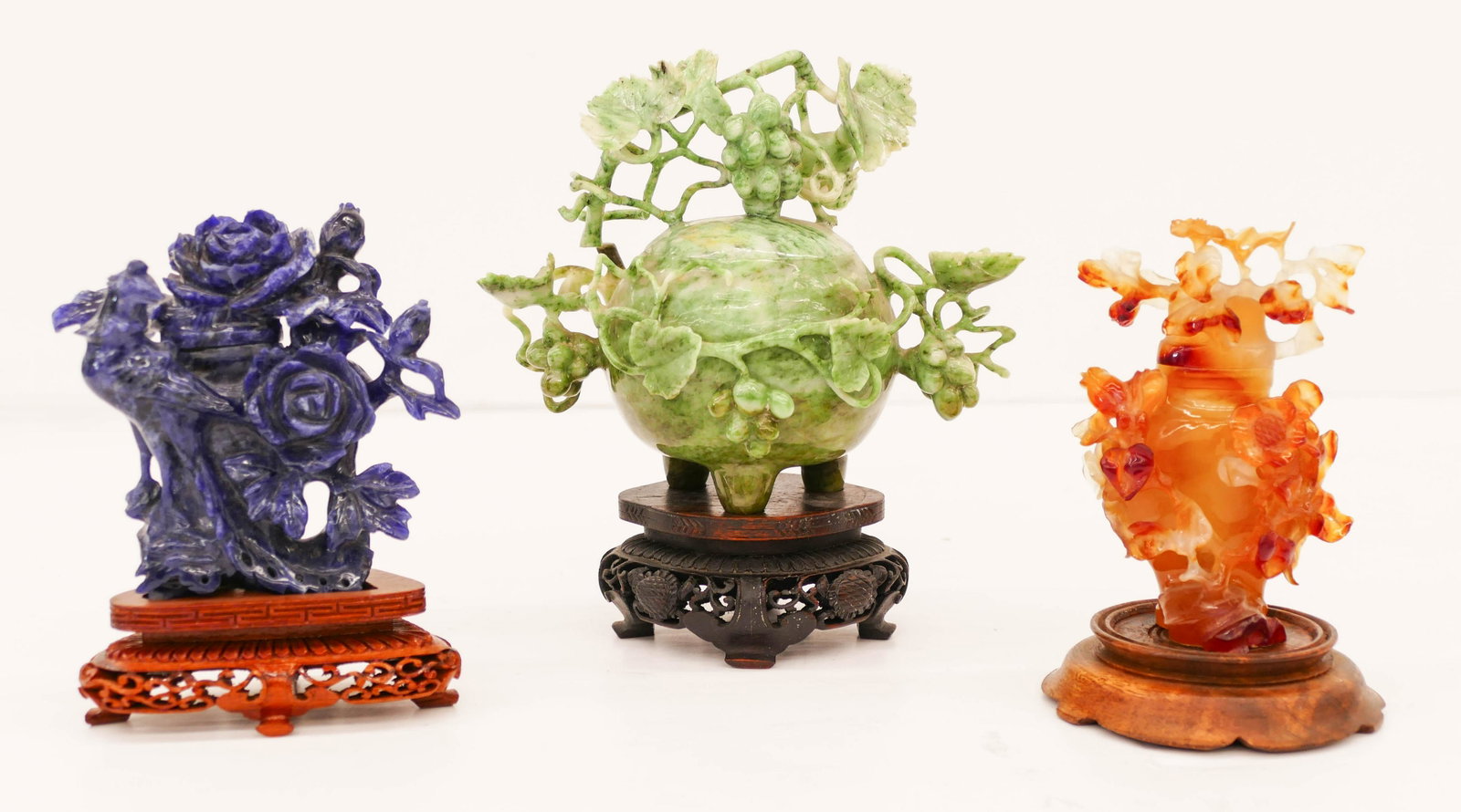 3pc Chinese Hardstone Covered Vases and Censer on: 3pc Chinese Hardstone Covered Vases and Censer on Stands 5'' to 7''. Includes a carved carnelian agate covered vase, a lapis covered vase with phoenix, and a tripod jade grape censer. Pierced rosewood