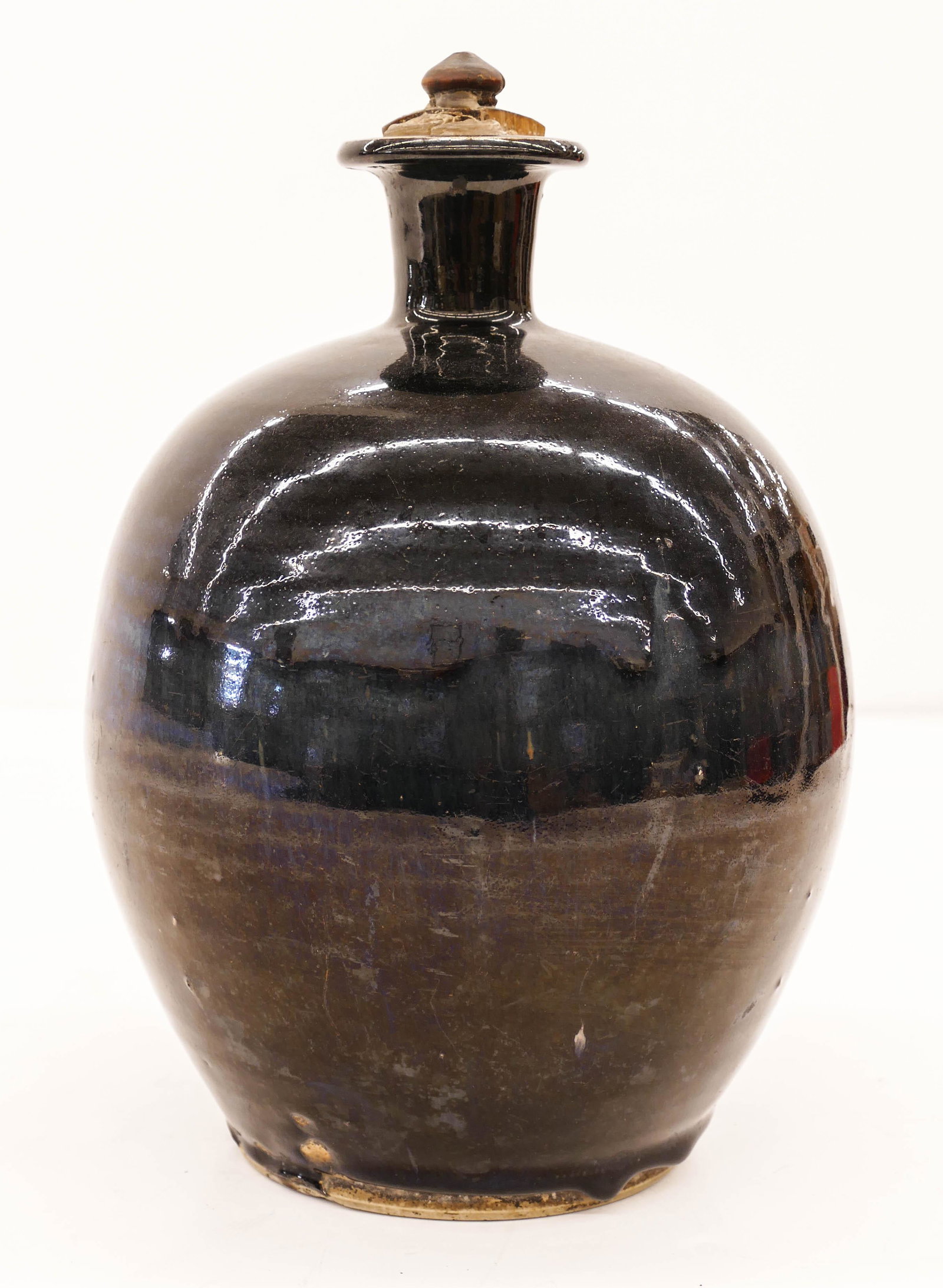 Chinese Qing Henan Black Glazed Bottle 12''x7''. Dark: Chinese Qing Henan Black Glazed Bottle 12''x7''. Dark dripping henan black glaze with original wood stopper. Kiln chipping to bottom edge, original to manufacture. 18th or 19th century. (AR)