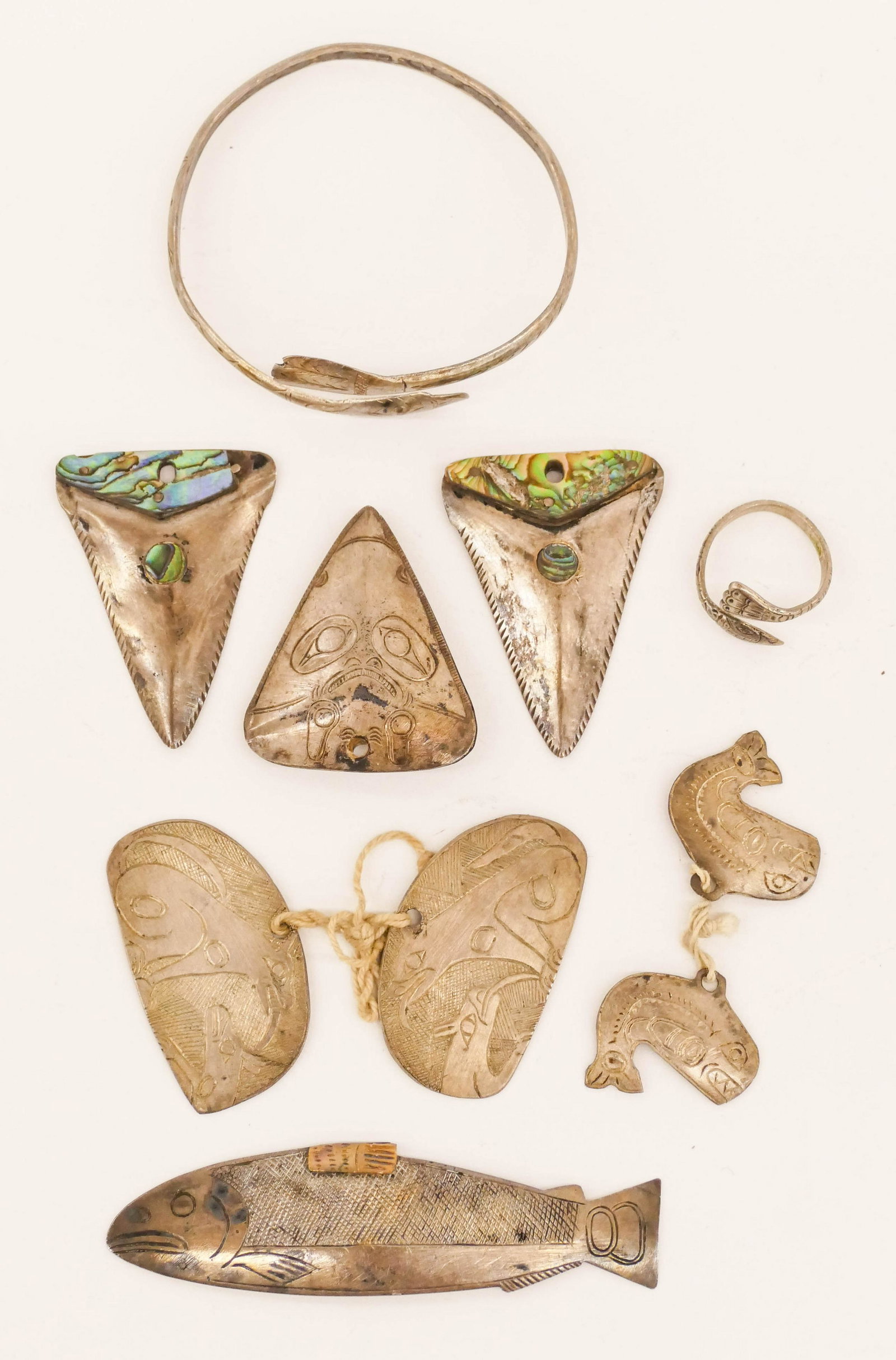 10pc Old Northwest Coast Native Silver Jewelry 1'' to: 10pc Old Northwest Coast Native Silver Jewelry 1'' to 3.25'' Long. An early group of hand made u-form jewelry including fish, wolf, bird, shark, and whale motifs. Unmarked. Some wear from age. Early t