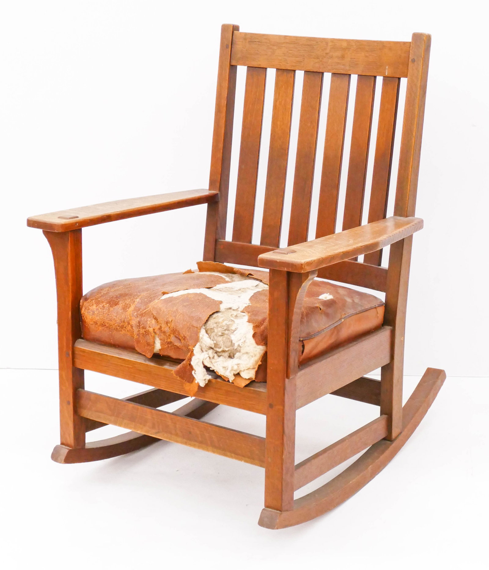 L&J.G. Stickley Oak Mission Rocker 35''x27''x29''. A: L&J.G. Stickley Oak Mission Rocker 35''x27''x29''. A period arts and crafts rocker with burned in mark on back lower panel. Original brown leather cushion in as-is condition. Some minor surface wear f