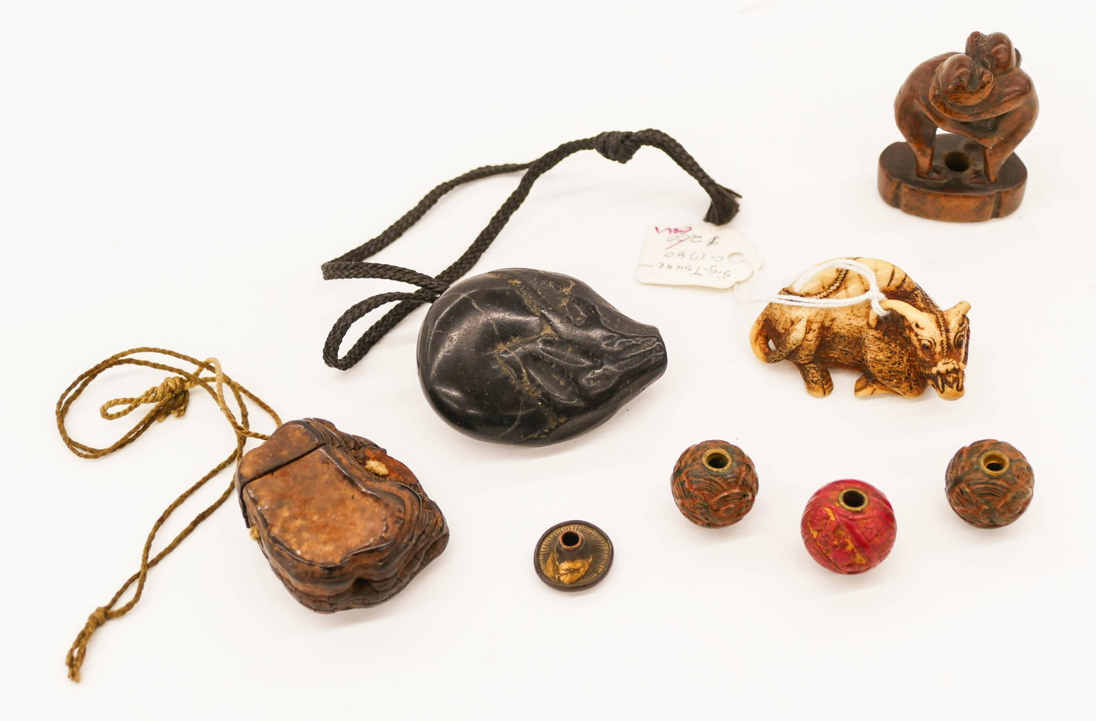 8pc Old Japanese Netsuke & Ojime Beads .75'' to 2'': 8pc Old Japanese Netsuke & Ojime Beads .75'' to 2''. Includes three lacquered ojime beads, one shakudo ojime, a horn reclining ox netsuke signed Tsune, an early boxwood netsuke of monkeys, black stone