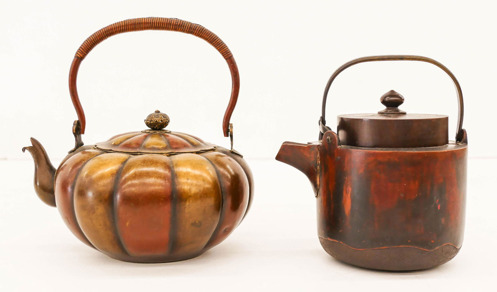 2pc Japanese Meiji Tea Kettles 6'' to 7'': 2pc Japanese Meiji Tea Kettles 6'' to 7''. Includes a lacquered copper kettle and a lacquered wood kettle (signed with crack to side of spout). Scattered surface wear from age. Collection of W. Gordon