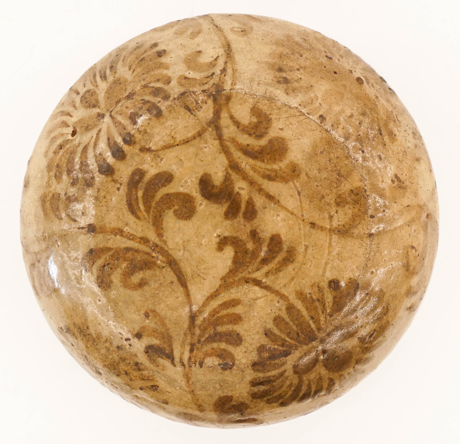 Korean Goryeo Peony Decorated Celadon Lid 2.25''x7'': Korean Goryeo Peony Decorated Celadon Lid 2.25''x7''. An early ceramic jar or box lid with underglaze iron brown scrolling peony motifs. It has a 2'' crack on one side. 12th century. Collection of W. 