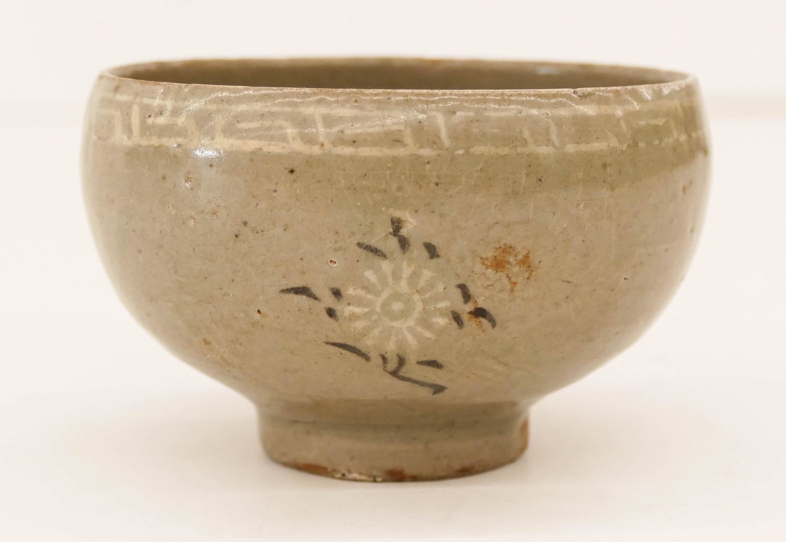 Korean Goryeo Inlaid Celadon Small Bowl 2''x3.5'': Korean Goryeo Inlaid Celadon Small Bowl 2''x3.5''. An early ceramic small bowl or cup with three inlaid flower motifs and decorated exterior rim. Slight hairline crack. 12th to 13th century.
