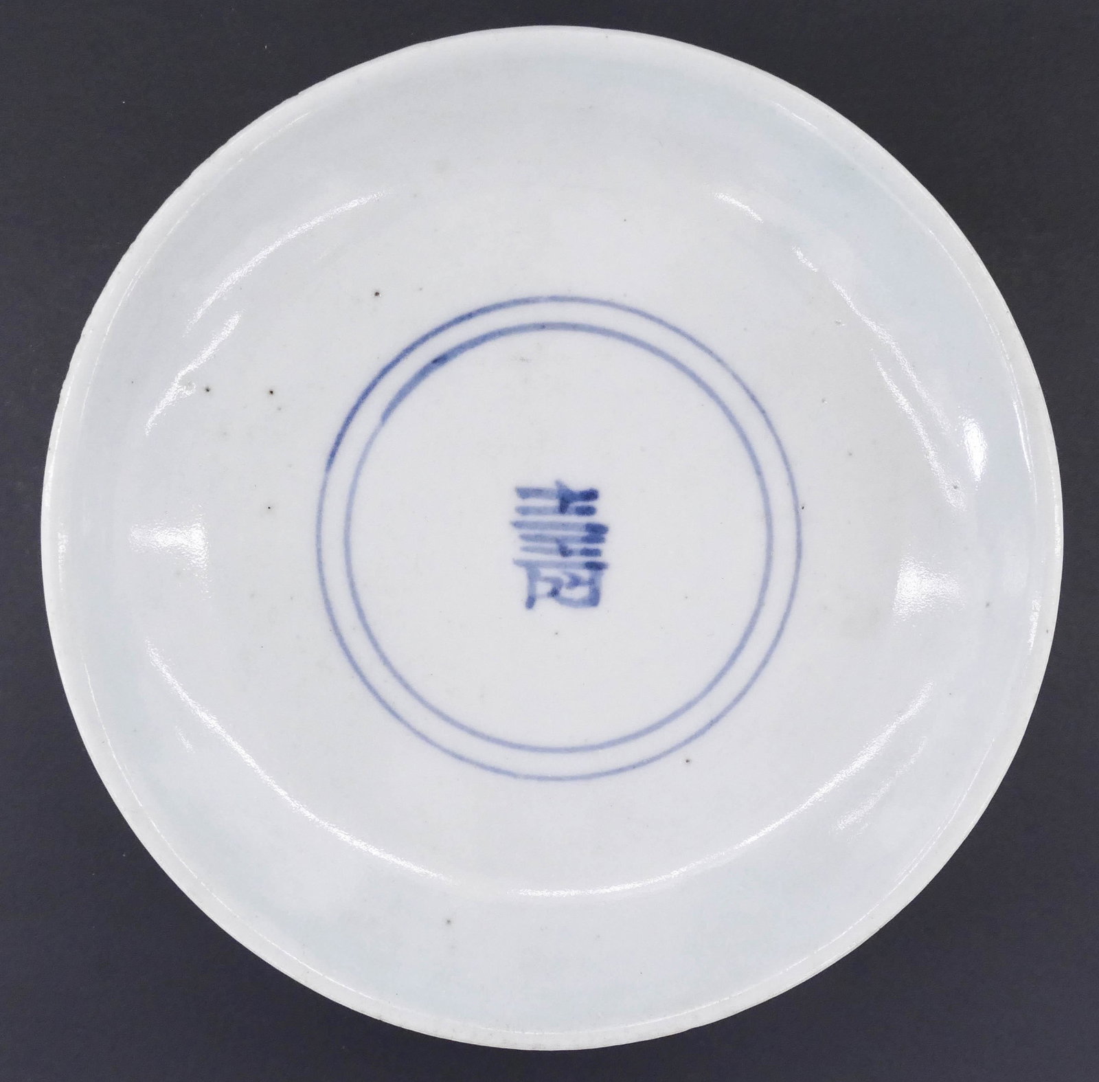 Korean Joseon Blue and White Dish 1.25''x4.75'': Korean Joseon Blue and White Dish 1.25''x4.75''. Blue underglaze decorated porcelain with central character and ring motif. Some very slight glaze roughness to edge. 19th century. Collection of W. Gor