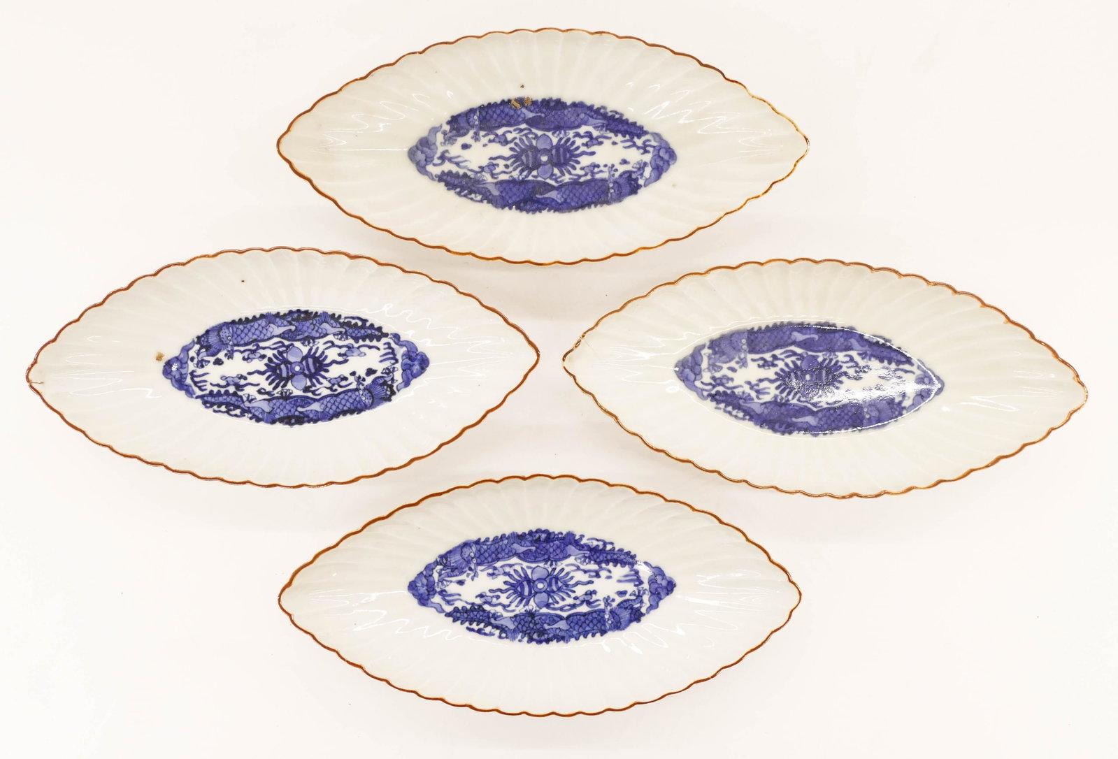 Set of 4 Japanese Edo Kakiemon Boat Shaped Dishes: Set of 4 Japanese Edo Kakiemon Boat Shaped Dishes 1.25''x9''x4''. Matching set of blue underglaze scalloped dishes with swirling dragon motifs. Two have small firing cracks to end and one has slight f