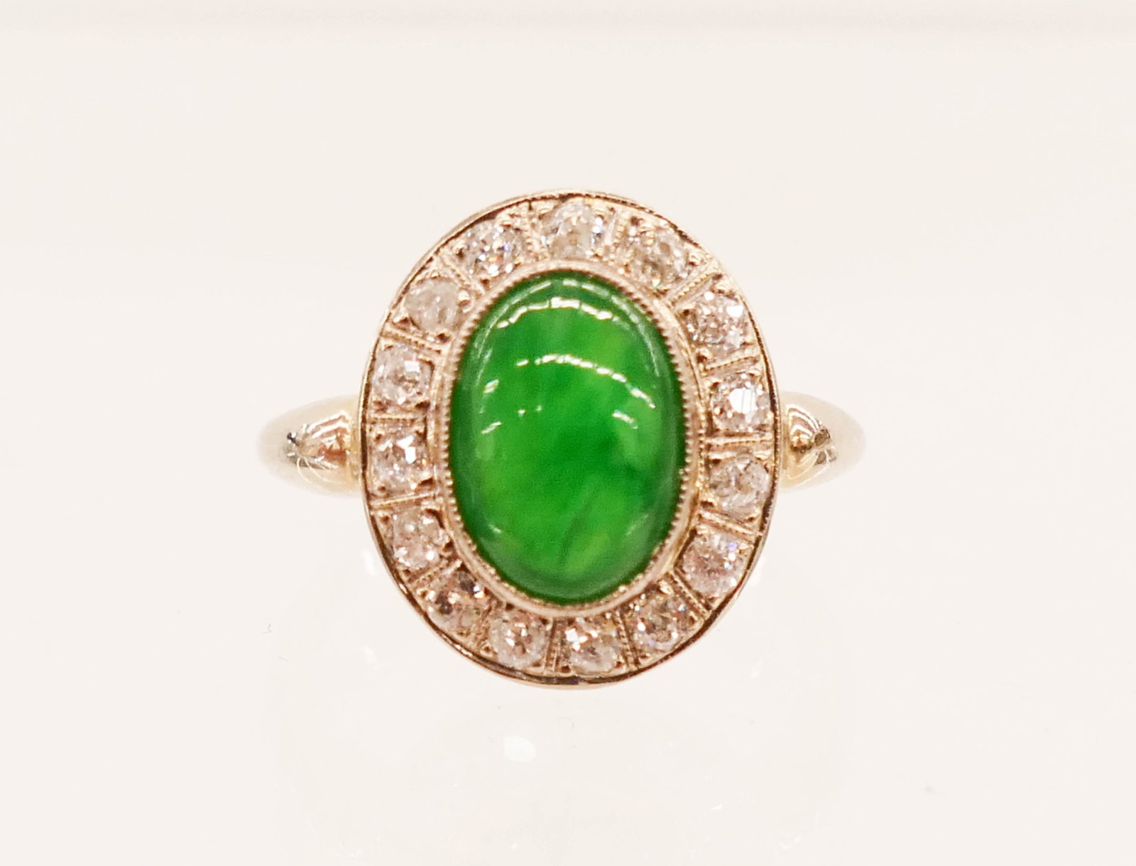 Lady's 14k Jadeite and Diamond Art Deco Ring Size 5.5: Lady's 14k Jadeite and Diamond Art Deco Ring Size 5.5. Fine apple green jade cabochon 10x7.5mm approx. is surrounded by (15) mixed cut diamonds of 2mm. White gold mount is marked ''14K EWG''. It weigh