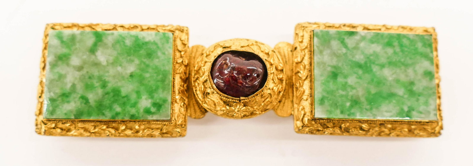 Chinese Qing Jadeite Gilt Metal Buckle: Chinese Qing Jadeite Gilt Metal Buckle 4.25''x1.25''. A repousse worked gilt metal buckle inset with green to gray jade panels 24x33mm. Also a natural amethyst pebble set in center 11x15mm. Scrolling 