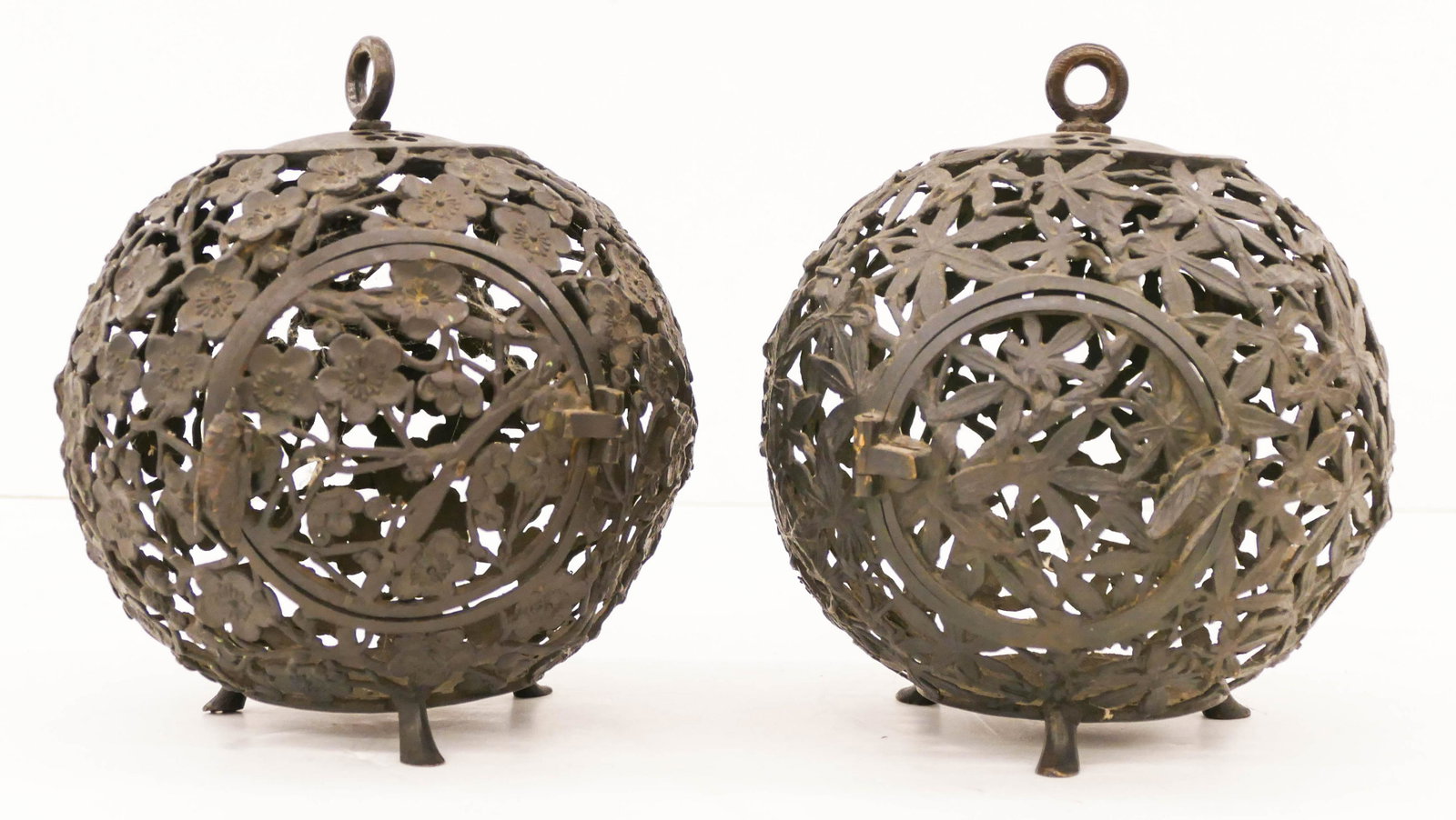 2pc Japanese Meiji Bronze Ball Lanterns 8"x7": 2pc Japanese Meiji Bronze Ball Lanterns 8''x7''. A duo of footed pierced lanterns with cherry blossom and leaf motifs. Round doors with figural cicada latches. Marked on bottom. Some minor surface wea
