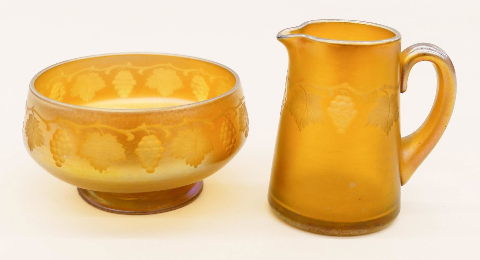 L.C. Tiffany Favrile Grape Vine Sugar and Creamer: L.C. Tiffany Favrile Grape Vine Sugar and Creamer. A miniature gold iridescent glass set with intaglio cut grape vine motif. They measure 1.75'' and 2.75'' tall. Both clearly signed. Creamer has a som