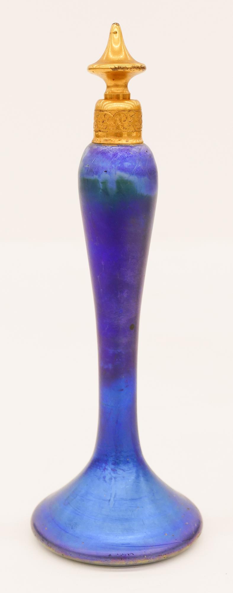 Steuben Blue Aurene DeVilbiss Perfume Bottle: Steuben Blue Aurene DeVilbiss Perfume Bottle 7.75''x2.5''. A gilt stoppered glass bottle. Marked DeVilbiss on bottom. A few minor surface marks. Overall excellent condition.
