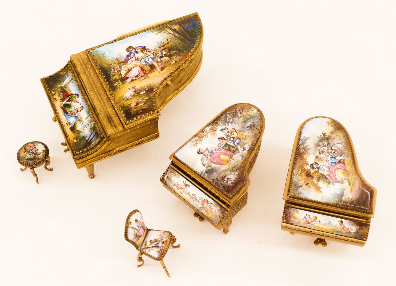 3pc European Enameled Miniature Piano Music Boxes: 3pc European Enameled Miniature Piano Music Boxes. Includes a duo of matching polychrome enameled metal pianos with romanticist courting scenes and putti 2.5''x4.5''. One has a non-working music box a