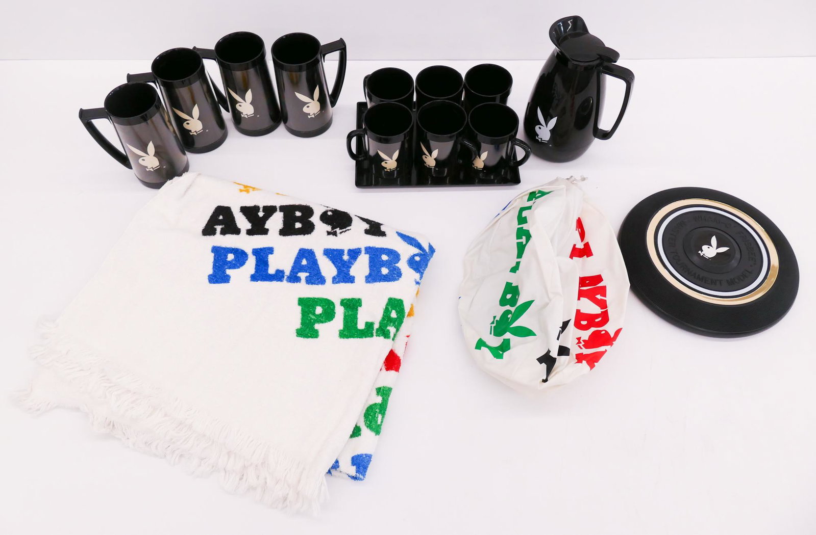 Group Vintage Playboy Items: Group Vintage Playboy Items. Includes 4pc Plastic Beer Steins, 6pc Plastic Coffee Mugs, 1 Plastic Tray that holds the 6 Coffee Mugs, 1 Black Plastic Coffee Carafe, 1 Beach Ball, 1 Frisbee, and 1 Beach