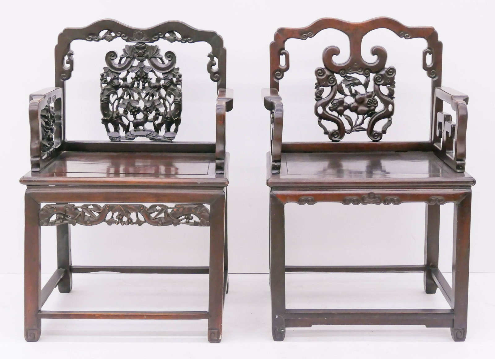 2pc Chinese Qing Rosewood Armchairs: 2pc Chinese Qing Rosewood Armchairs 39''x24''x19''. Heavily carved pierced back armchairs with pomegranate and grape motifs. Pomegranate chair has old repairs to one arm. 19th century, Qing dynasty.