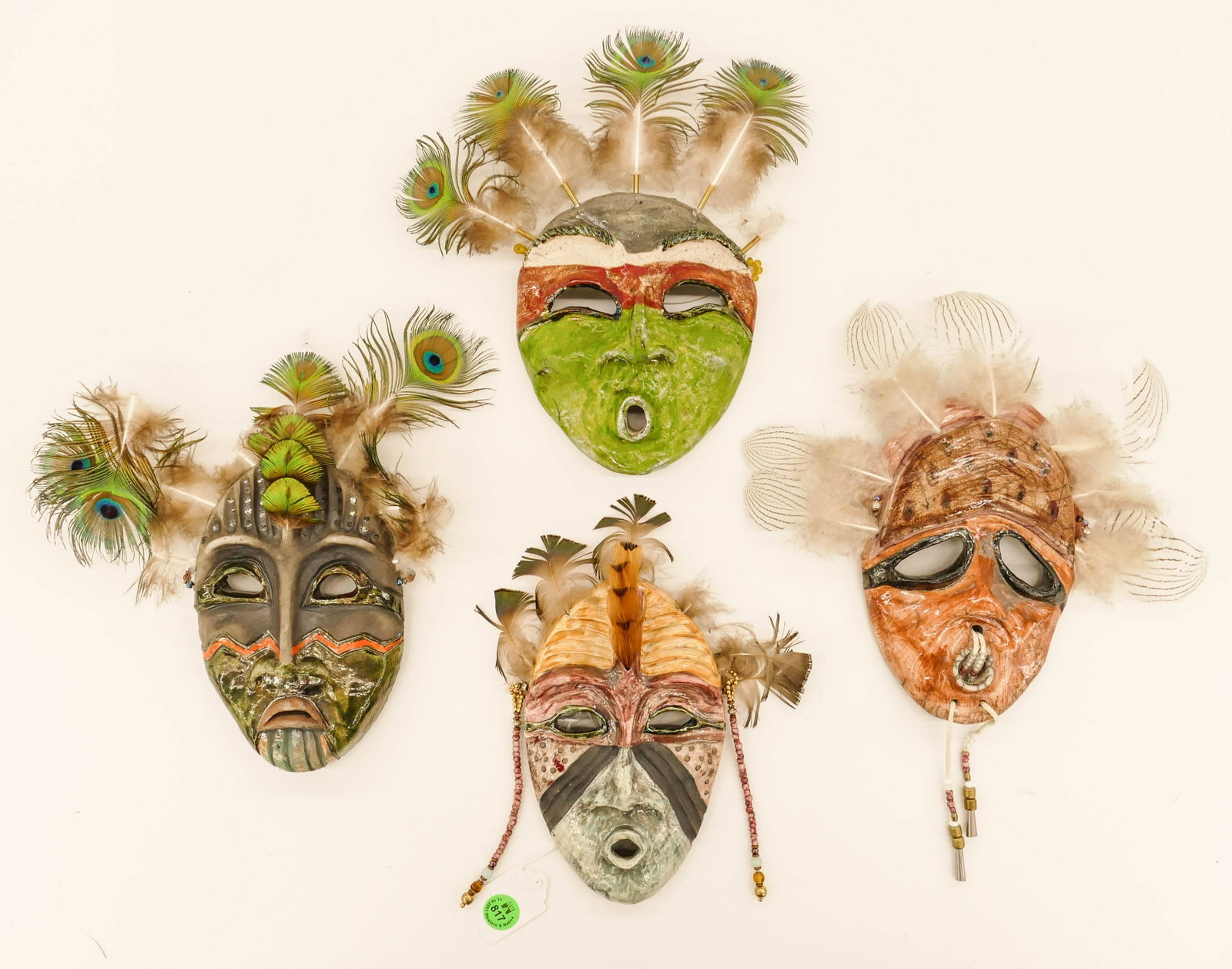 4pc Lillian Pitt Colorful Small Ceramic Masks: 4pc Lillian Pitt (b.1943 Wasco) Colorful Small Ceramic Masks. All approx. 8''x6'' each. Mixed media with feathers and beads. Includes ''katchia Stick Indian'', ''Pacific Driftwood Spirit'', ''Shitilce