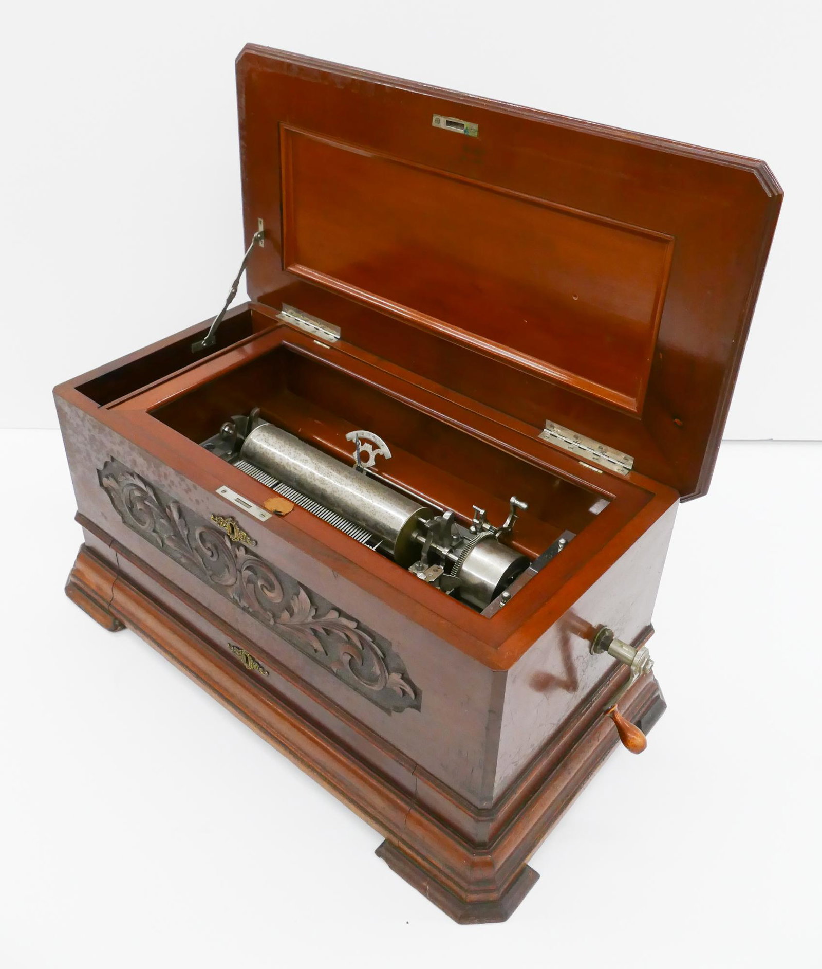 Swiss Cylinder Music Box: Antique Swiss Cylinder Music Box in Carved Mahogany Box. Likely Columbia, serial appears to read 106622. Box measures 12.5x25x15'' with carved scroll decoration on front and lower drawer with addition