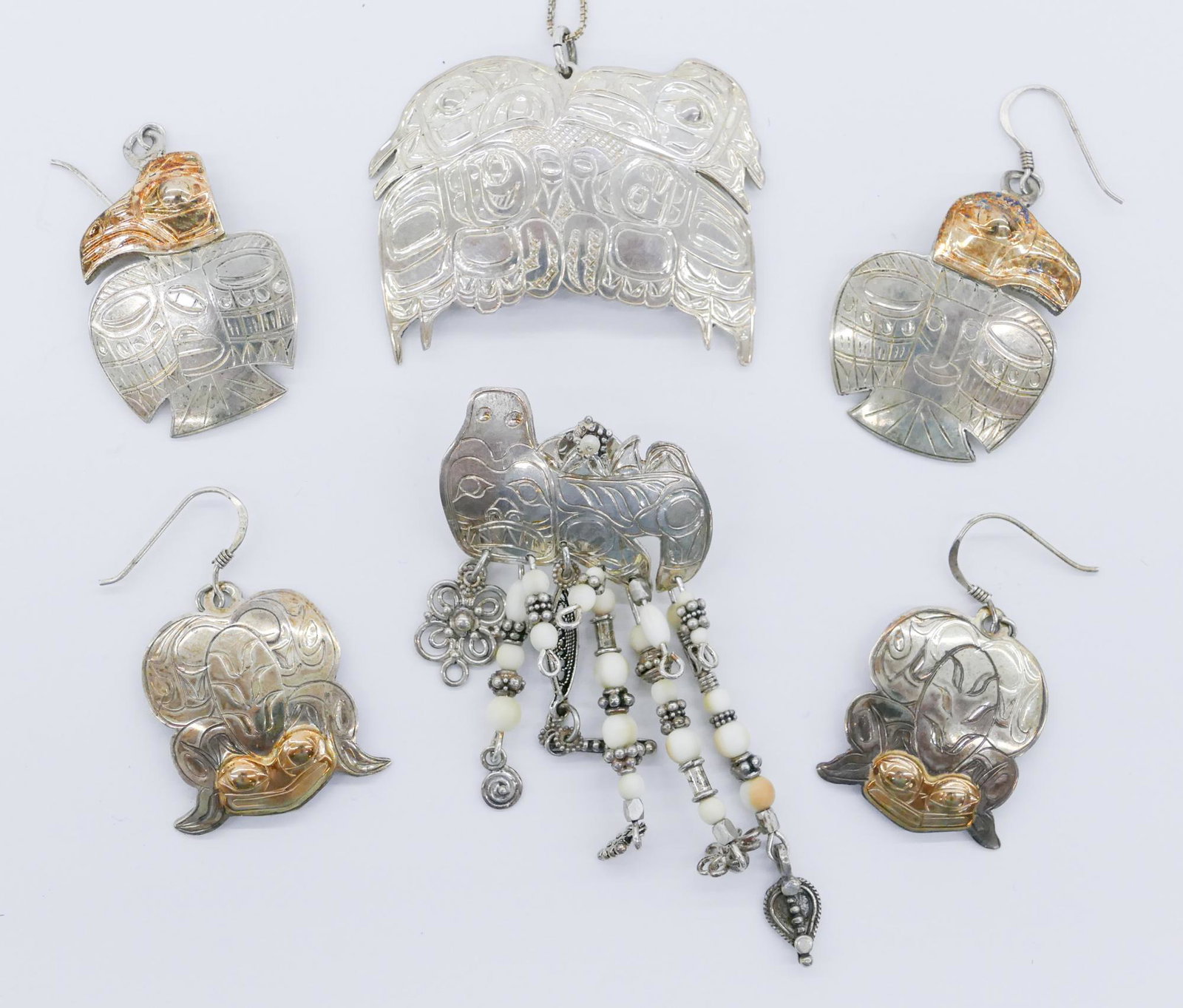4pc Gene Chilton Tlingit 14k and Sterling Jewelry: 4pc Gene Chilton (20/21st Cent. Tlingit) 14k and Sterling Jewelry 1'' to 2.5''. Includes a pair of raven earrings, a pair of frog earrings, dogfish dangling brooch, and a love bird pendant necklace. S